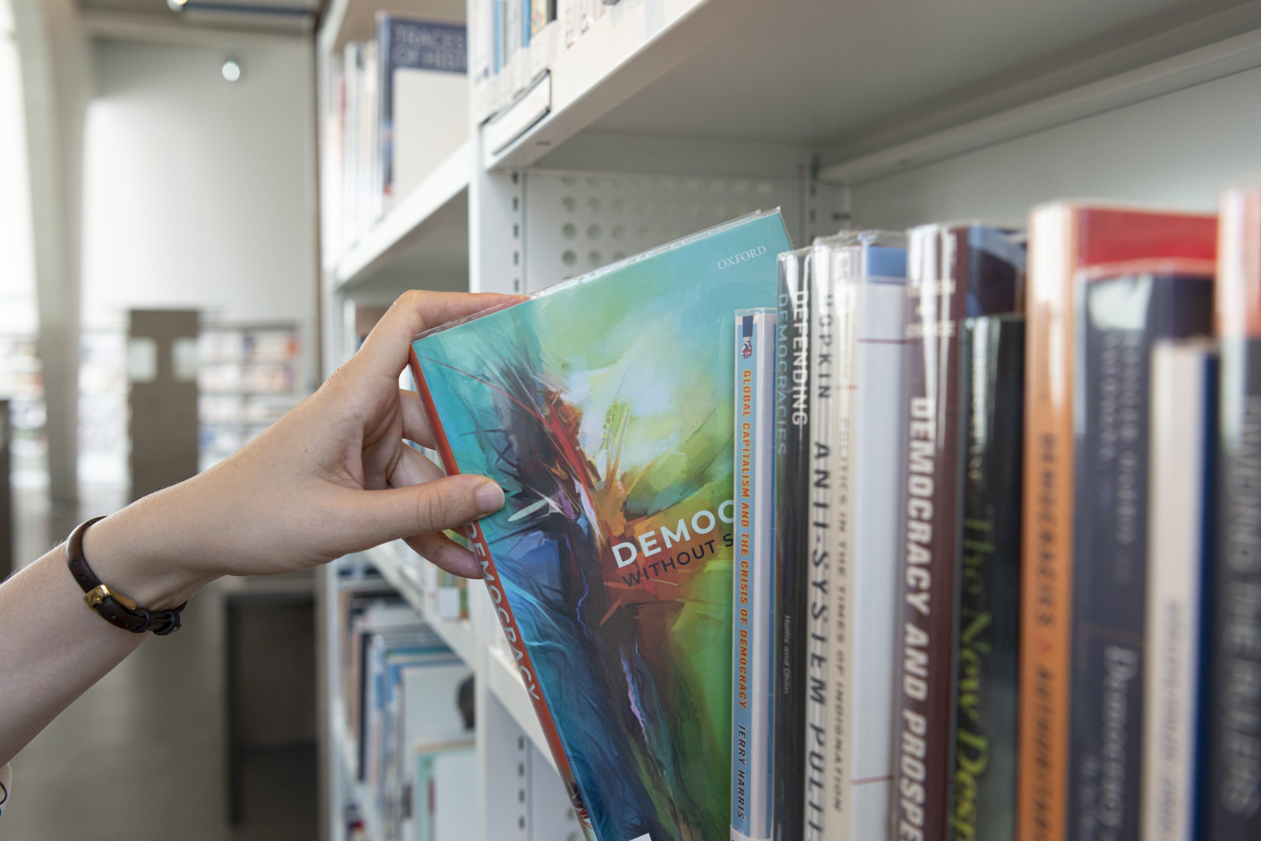 Photo d'un rayonnage, une main en sort un livre