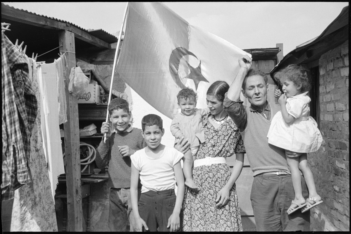 Photo d'une famille algérienne devant un drapeau de l'Algérie